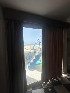 a room with a window with a view of the beach at مجمع ديار بالساحل الشمالي in Sidi Kirayr +5 photos
