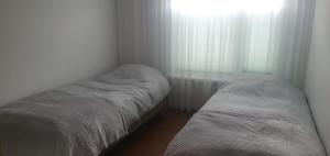 two beds in a small room with a window at Mahlamäe külaliskorter in Rapla