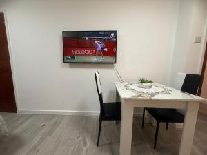 ファーナムにあるFlat in Surreyの白いテーブル(椅子付)、壁掛けテレビ