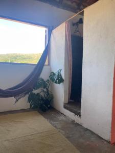 Una habitación con una ventana y una planta en la esquina. en Hospedagem Toca das lobas, en São Thomé das Letras 8 fotos más
