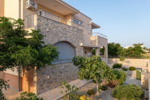 a house with a brick wall and a balcony at Apartmani Lucija in Povljana