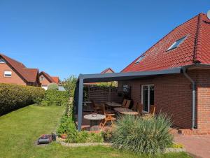 a garden with a patio with a table and chairs at Ferienhaus Lina in Südbrookmerland
