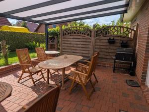 a patio with a table and chairs and a grill at Ferienhaus Lina in Südbrookmerland +11 photos