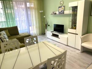 a living room with a couch and a table and a television at Апартамент Green Lines in Primorsko
