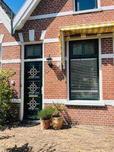 a brick house with two black doors and two potted plants at House 'n Cheese - Alkmaar in Alkmaar