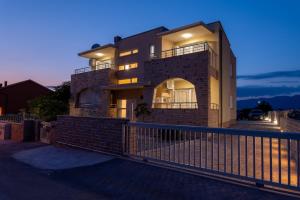 a house with a fence in front of it at Apartmani Lucija in Povljana