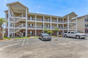um grande edifício com dois carros estacionados num parque de estacionamento em 1 Mi to Beach Family Condo in North Myrtle Beach! em Myrtle Beach