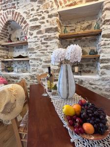 a table with a bowl of fruit and a vase of flowers at Filipa Gardens in Limenas