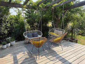 a patio with two chairs and a swing at Maison des conches in Longeville-sur-Mer