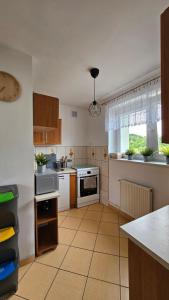 a kitchen with white appliances and a large window at Apartament RYŚ Polanica Zdrój in Polanica-Zdrój +7 photos