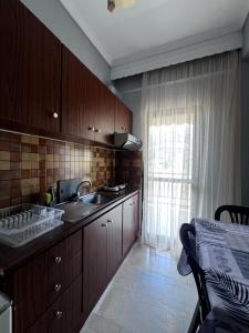 eine Küche mit Holzschränken und Spüle und einem Fenster in der Unterkunft Almond Apartments Sun and Sea in Asprovalta