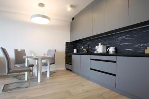 kuchnia ze stołem i czarno-białą ścianą w obiekcie LUX Apartament Rogowo Pearl w Rogowie