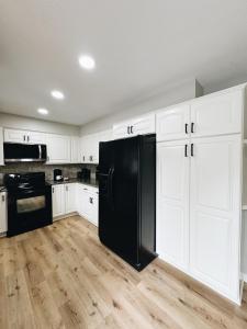 a black refrigerator in a kitchen with white cabinets at Newly Renovated Home With Pool in Omaha
