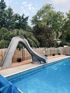 a slide in a pool next to a wooden fence at Newly Renovated Home With Pool in Omaha