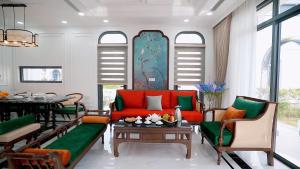 a living room with a red couch and a table at Annam Villa Sonasea Vân Đồn in Thâm Câu