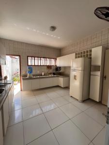 a kitchen with white appliances and white tile walls at Ampla Casa Duplex com 4 suítes in Teresina