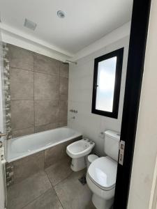 a bathroom with a toilet and a tub and a sink at Departamento Confort AVI in Salta +2 photos