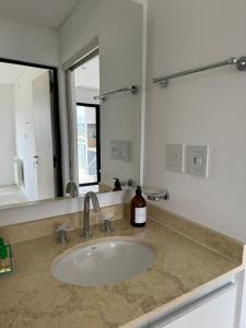 a bathroom sink with a large mirror and a bottle of soap at Departamento Confort AVI in Salta