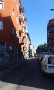 una calle de la ciudad con coches aparcados en el lateral de un edificio en Appartamento Via Comune Antico, en Milán