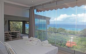 ein Schlafzimmer mit einem großen Fenster und Handtüchern auf einem Bett in der Unterkunft The Beach House - Apartments & Studios in Afytos
