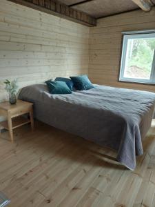 a large bed in a wooden room with a window at Saimaan Kodikas rantatalo in Savonlinna