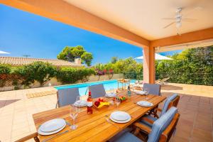 a wooden table and chairs on a patio with a pool at Villa Ionian Rose in Trapezaki