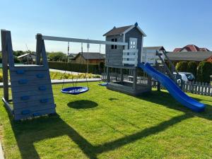 a playground with two swings and a slide at Domki Maju Maj in Darłowo
