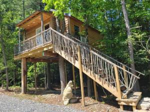 a tree house in the woods with a staircase at Treehouses at Lake Mountain Manor in Princeton