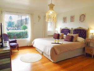 a bedroom with a bed with a chandelier and a window at La Aguada in El Bolsón +49 photos