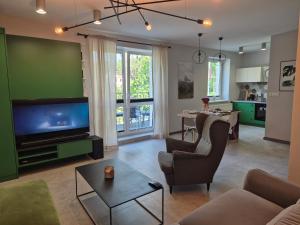 a living room with a couch and a tv and a table at Apartament z widokiem na Dom Oficera in Borne Sulinowo