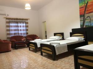 RubikにあるHotel Xhejのベッド4台、椅子、ソファが備わる客室です。