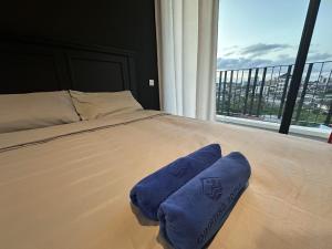 a bed with a blue towel on it in front of a window at Tropics City Supreme Black Theme Large Balcony City View至尊黑主题大阳台城市风景民宿 in Kuching +28 photos