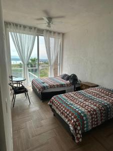 Un dormitorio con dos camas y una mesa y una ventana. en House in Teques Rooftop with view and pool for 15, en Tequesquitengo