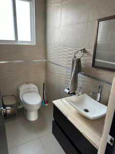 Un baño con un inodoro blanco y un lavabo. en House in Teques Rooftop with view and pool for 15, en Tequesquitengo
