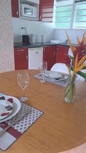 a table with two wine glasses and a vase of flowers at Studio bord de mer in Schœlcher