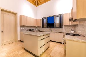 a large kitchen with white cabinets and wooden floors at Casa Ceiba in La Romana
