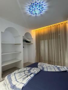 a bedroom with a bed and a blue chandelier at Dar Omi Aïcha in Kerkouene