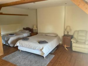 two beds in a bedroom with a chair and a couch at Kanevedenn in Val Couesnon