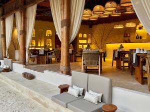 a restaurant with tables and chairs and a couch at Kai Zanzibar Hotel and Spa in Nungwi