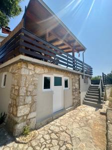 a stone building with a white door and a wooden roof at Villa Si'Seta in Krk