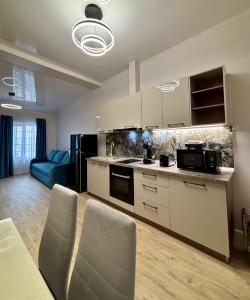 a kitchen with white cabinets and a blue couch at MaRailiS Port Apart Mangalia in Mangalia