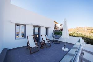 Un balcón con dos sillas y una sombrilla. en Stonehill Suites Ano Syros, en Ano Syros