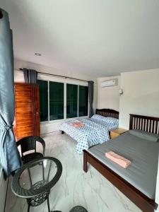 Un dormitorio con dos camas y una mesa y sillas. en R-Rich Homestay อาริชโฮมสเตย์, en Betong