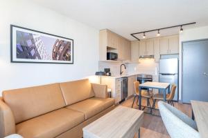 a living room with a couch and a kitchen at Sandman Suites Vancouver on Davie in Vancouver