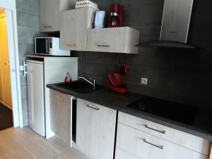 a kitchen with white cabinets and a black wall at Résidence Olympia 2000 - Studio 4 à 5 personnes - Vue imprenable MAE-8464 in Montgenèvre