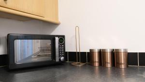 a microwave oven sitting on a kitchen counter next to two silver cylinders at Free Parking & Garden & Central Contractor in Bedford