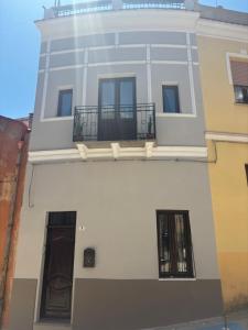 a white building with two windows and a balcony at Domo Via Ozieri in Iglesias