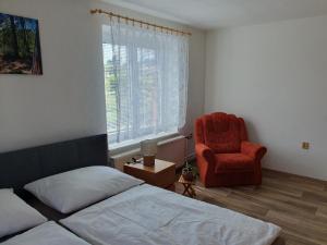a bedroom with a bed and a red chair at Apartmán Vilovka Slavonice in Slavonice