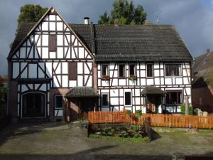Una casa grande blanca y negra con una valla. en Apartment in Ober Waroldern mit Sauna, en Oberwaroldern 32 fotos más