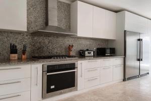 Una cocina con gabinetes blancos y un refrigerador de acero inoxidable. en Casa Chavon, en La Romana